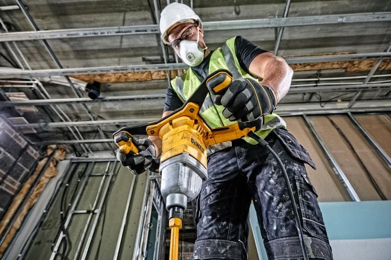 Person nutzt DEWALT DWD241 Rührwerk auf Baustelle, trägt Sicherheitsweste und Handschuhe.